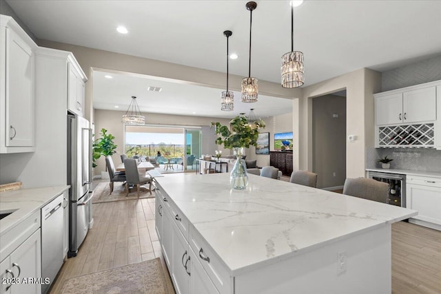 kitchen featuring stainless steel appliances, a kitchen island, hanging light fixtures, and white cabinets