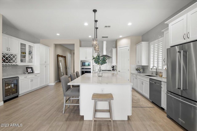 kitchen featuring wine cooler, sink, a kitchen island, stainless steel appliances, and white cabinets