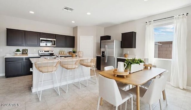 kitchen with a center island with sink, visible vents, appliances with stainless steel finishes, light countertops, and recessed lighting