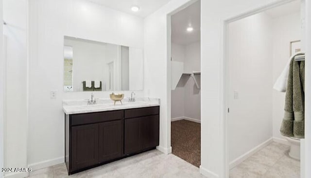 bathroom featuring double vanity, baseboards, and a sink