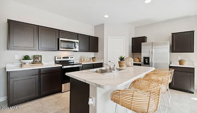 kitchen featuring a breakfast bar, light countertops, appliances with stainless steel finishes, a kitchen island with sink, and a sink