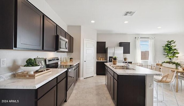 kitchen featuring stainless steel appliances, a sink, visible vents, light countertops, and an island with sink