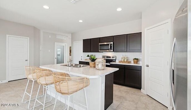 kitchen featuring appliances with stainless steel finishes, recessed lighting, dark brown cabinetry, and an island with sink