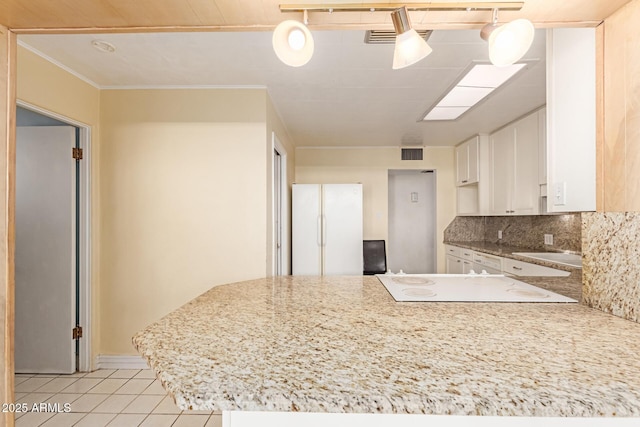 kitchen featuring light tile patterned floors, sink, white cabinetry, light stone countertops, and decorative backsplash