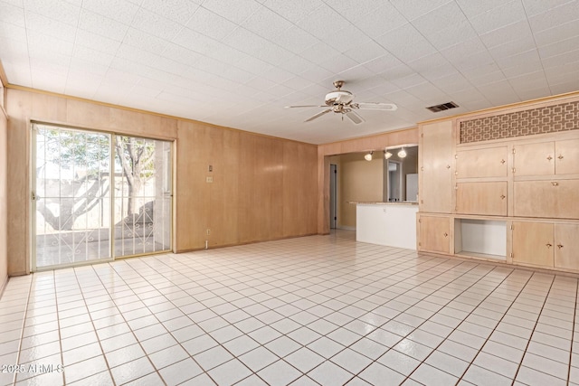 unfurnished living room featuring crown molding, light tile patterned floors, ceiling fan, and wood walls