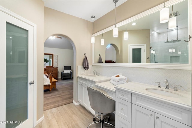 bathroom featuring tasteful backsplash, vanity, wood-type flooring, and walk in shower