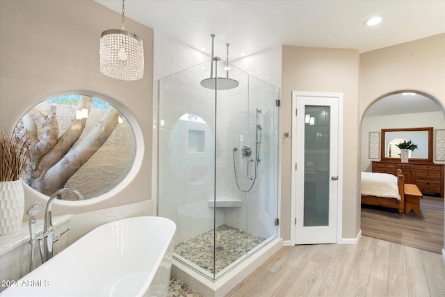 bathroom with plus walk in shower, hardwood / wood-style floors, and a notable chandelier