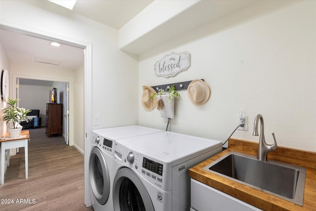 laundry room featuring sink, washer and dryer, and light wood-type flooring