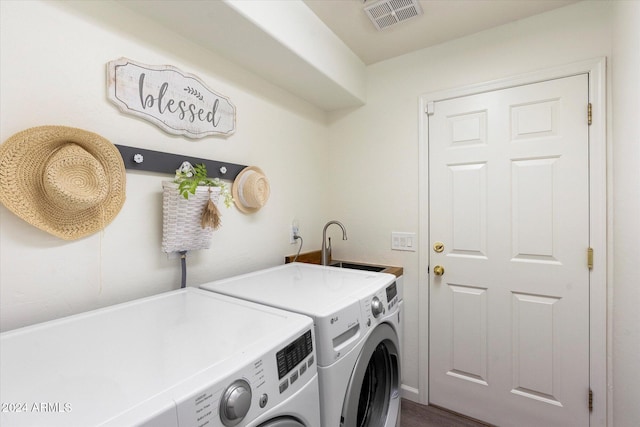 clothes washing area with washing machine and dryer, sink, and hardwood / wood-style flooring