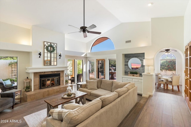 living room featuring a fireplace, high vaulted ceiling, and dark wood-type flooring