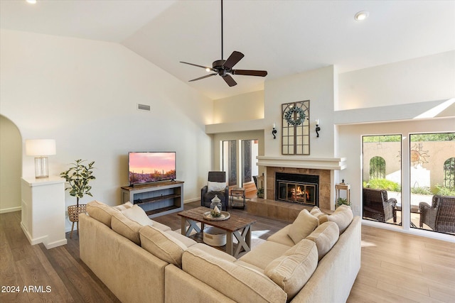 living room with a tile fireplace, ceiling fan, hardwood / wood-style floors, and high vaulted ceiling