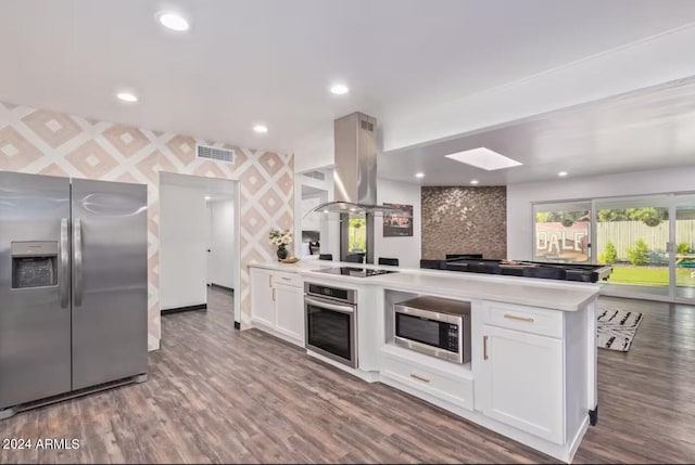 kitchen featuring island exhaust hood, kitchen peninsula, hardwood / wood-style floors, white cabinetry, and stainless steel appliances