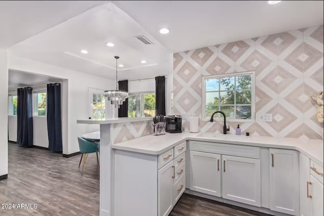 kitchen featuring kitchen peninsula, white cabinetry, pendant lighting, and dark hardwood / wood-style flooring