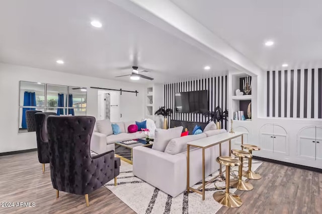 living room with beam ceiling, built in features, wood-type flooring, and a barn door