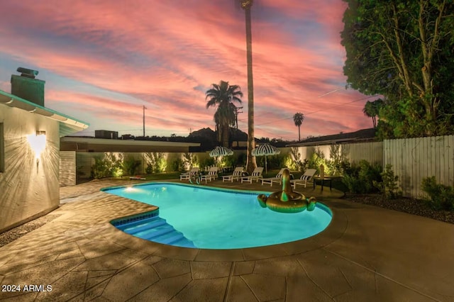 pool at dusk featuring a patio