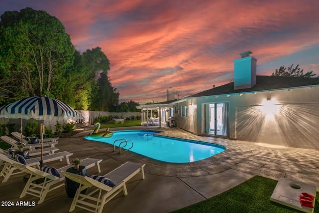 pool at dusk featuring a patio