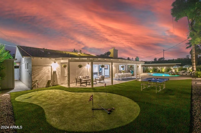 back house at dusk with an outdoor hangout area, a yard, and a patio