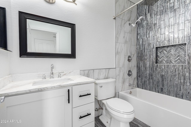 full bathroom with toilet, vanity, tile walls, and tiled shower / bath