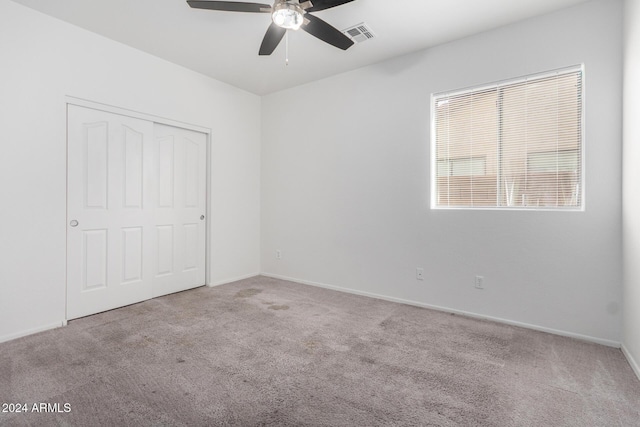 unfurnished bedroom featuring ceiling fan, a closet, and light carpet