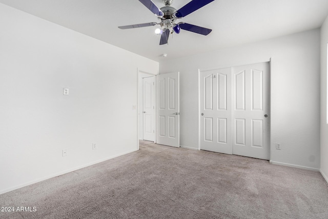 unfurnished bedroom featuring a closet, light colored carpet, and ceiling fan