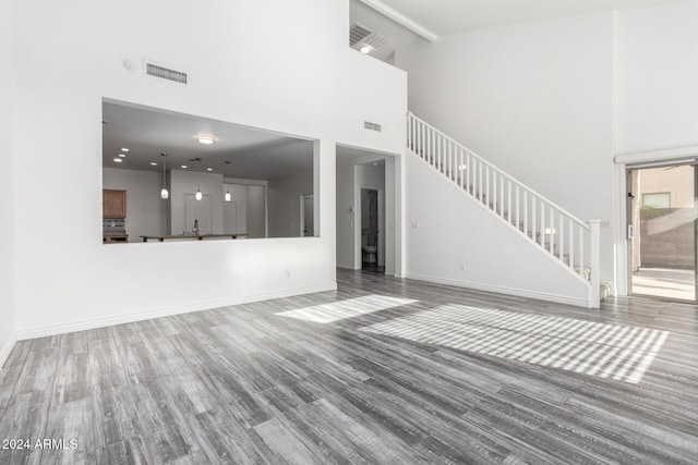 unfurnished living room with beam ceiling, hardwood / wood-style floors, and high vaulted ceiling