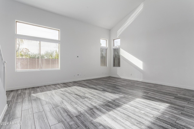 empty room with vaulted ceiling and hardwood / wood-style flooring