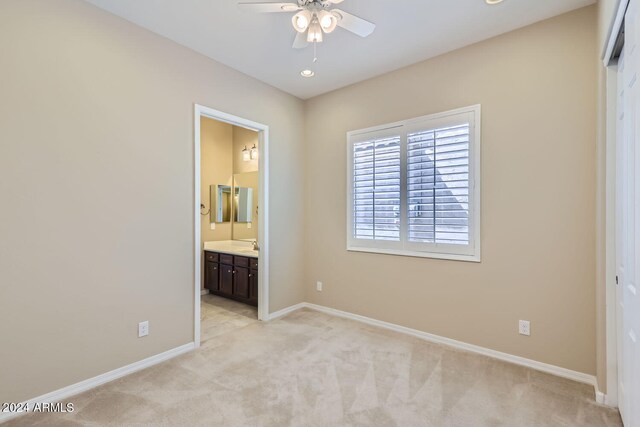 unfurnished bedroom with ensuite bath, ceiling fan, and light colored carpet