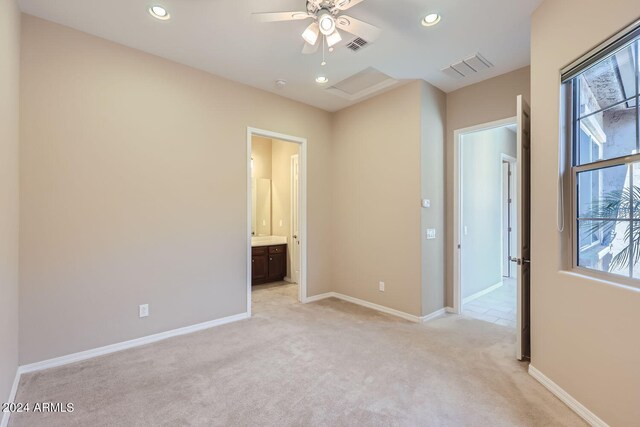 interior space featuring light carpet, connected bathroom, and ceiling fan