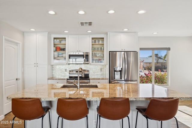 kitchen with a breakfast bar area, appliances with stainless steel finishes, white cabinetry, and sink