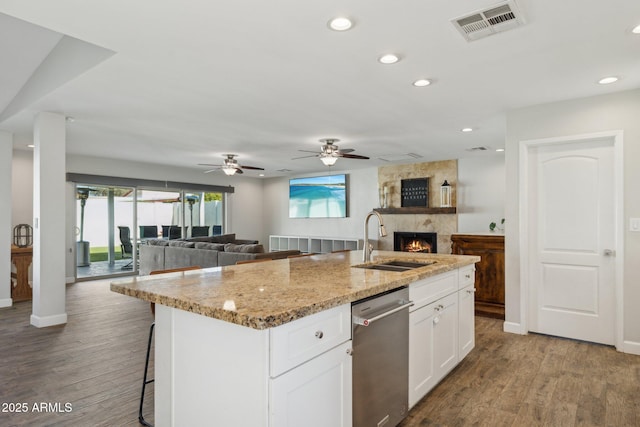 kitchen featuring sink, a kitchen island with sink, dark wood-type flooring, white cabinets, and light stone counters