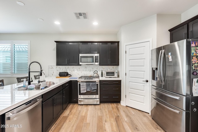 3699 E Sweetclover Ln, San Tan Valley, AZ 85140 - kitchen with light countertops, tasteful backsplash, stainless steel appliances, a sink, and visible vents