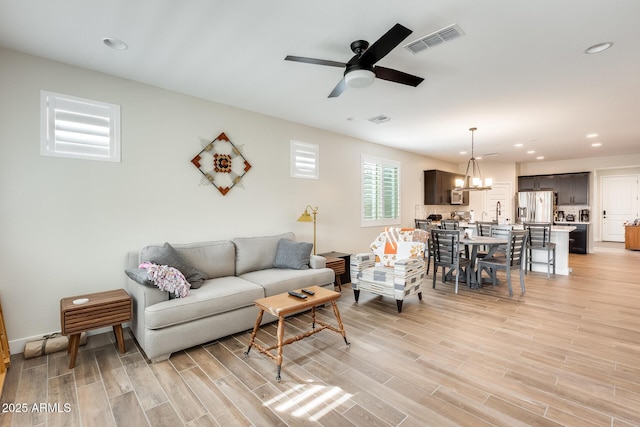 3699 E Sweetclover Ln, San Tan Valley, AZ 85140 - living area featuring light wood-type flooring, visible vents, recessed lighting, and ceiling fan with notable chandelier
