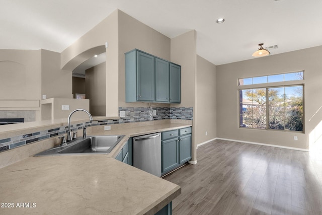 kitchen with sink, dishwasher, hardwood / wood-style floors, decorative backsplash, and kitchen peninsula