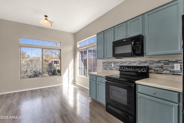 kitchen featuring backsplash, light hardwood / wood-style flooring, and black appliances