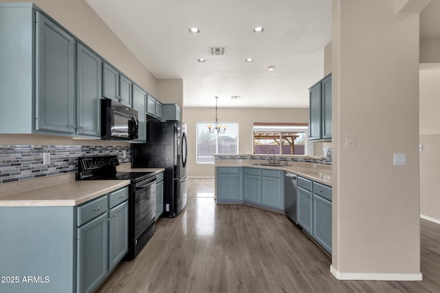 kitchen with sink, hanging light fixtures, tasteful backsplash, black appliances, and light hardwood / wood-style floors