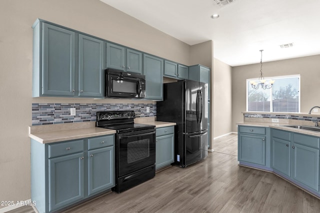 kitchen with decorative light fixtures, sink, backsplash, and black appliances