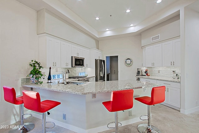 32472 N 68th Pl, Scottsdale, AZ 85266 - kitchen with a breakfast bar area, appliances with stainless steel finishes, visible vents, and tasteful backsplash