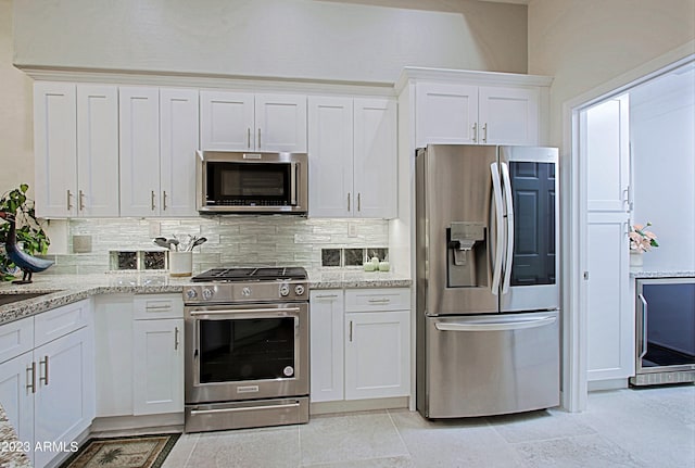 32472 N 68th Pl, Scottsdale, AZ 85266 - kitchen featuring light stone counters, beverage cooler, stainless steel appliances, white cabinetry, and decorative backsplash