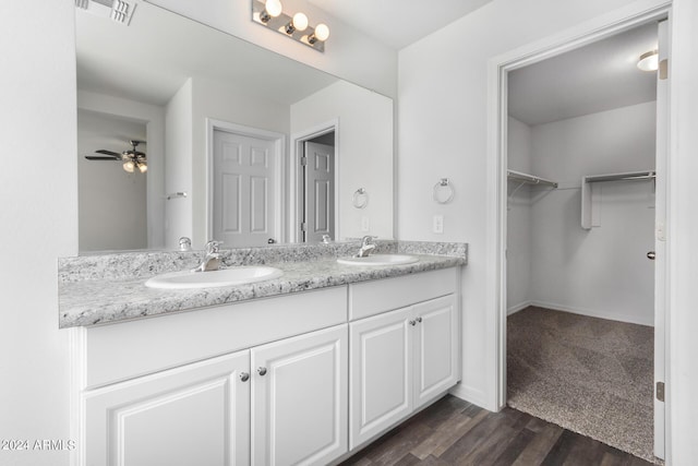 935 E Agua Fria Ln, Avondale, AZ 85323 - bathroom featuring double vanity, a spacious closet, ceiling fan, wood finished floors, and baseboards