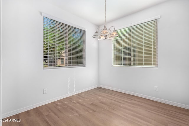 935 E Agua Fria Ln, Avondale, AZ 85323 - empty room featuring a chandelier, wood finished floors, baseboards, and plenty of natural light