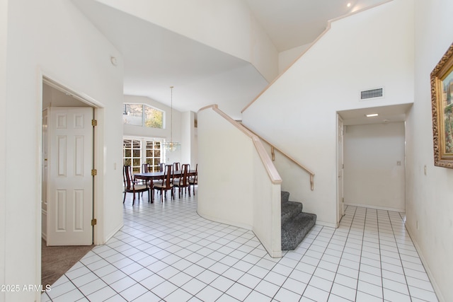 stairs featuring high vaulted ceiling and tile patterned flooring