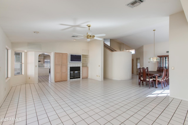 unfurnished living room featuring a tile fireplace, light tile patterned flooring, high vaulted ceiling, and ceiling fan