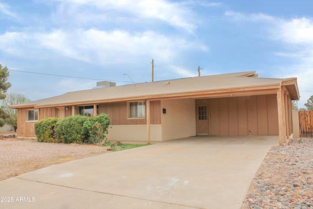 ranch-style home with an attached carport, driveway, and board and batten siding