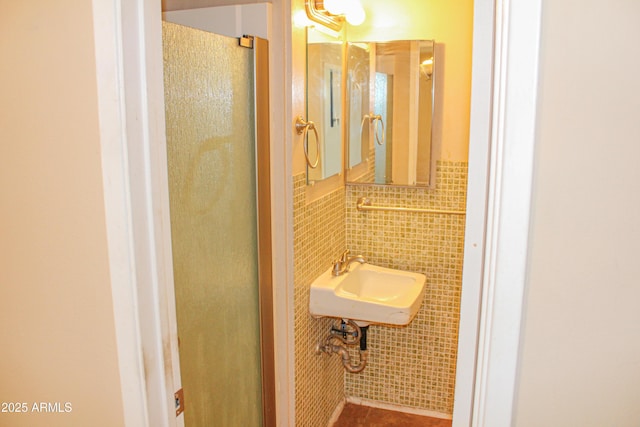 bathroom featuring tile walls, a sink, and a stall shower