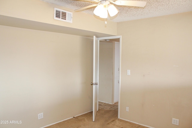 unfurnished bedroom featuring a textured ceiling, ceiling fan, light carpet, and visible vents