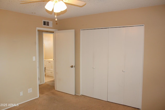unfurnished bedroom featuring visible vents, a closet, ceiling fan, a textured ceiling, and light carpet