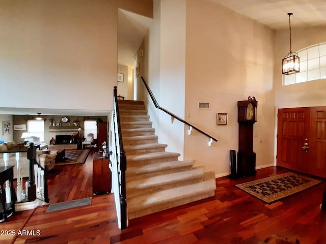 foyer with stairway, a high ceiling, wood finished floors, and baseboards