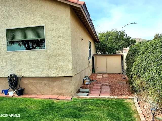 view of side of property featuring an outbuilding, a storage unit, and stucco siding