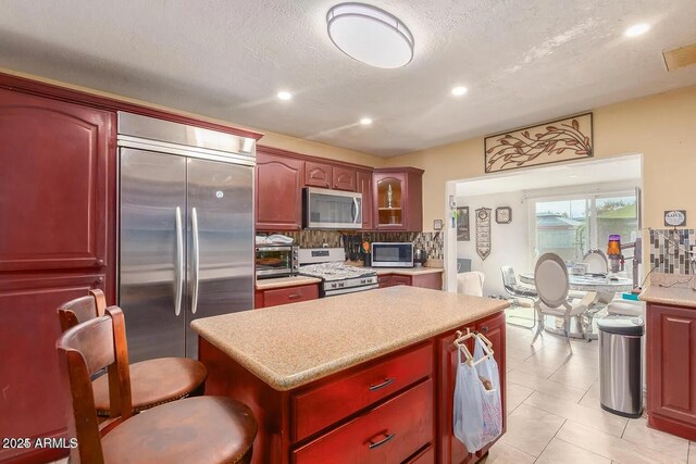 3121 W Greenway Rd, Phoenix, AZ 85053 - kitchen featuring tasteful backsplash, a center island, light countertops, dark brown cabinets, and stainless steel appliances