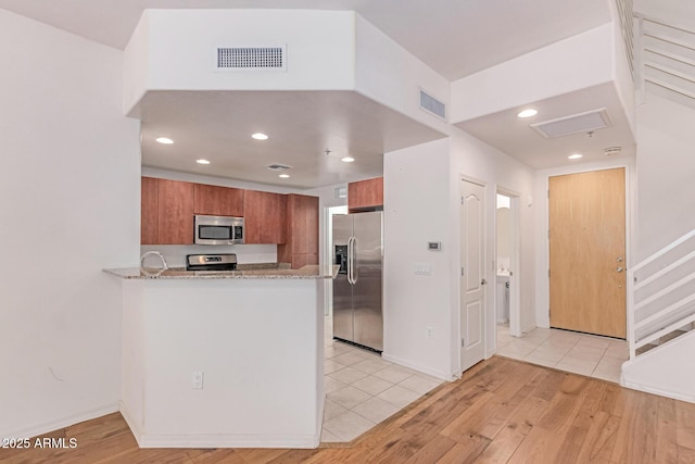 16 W Encanto Blvd Unit 26, Phoenix, AZ 85003 - kitchen with appliances with stainless steel finishes, brown cabinetry, light wood-style floors, a peninsula, and recessed lighting